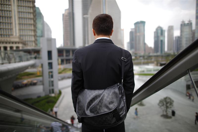 A business man rides an escalator in the financial district of Pudong